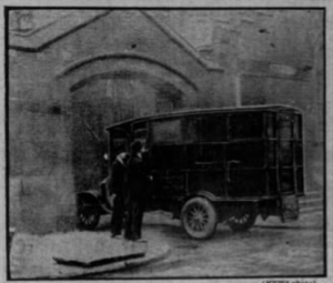 black and white photograph of police "black maria" with Mae West in it, two people trying to see inside as it drives into the Prison gates