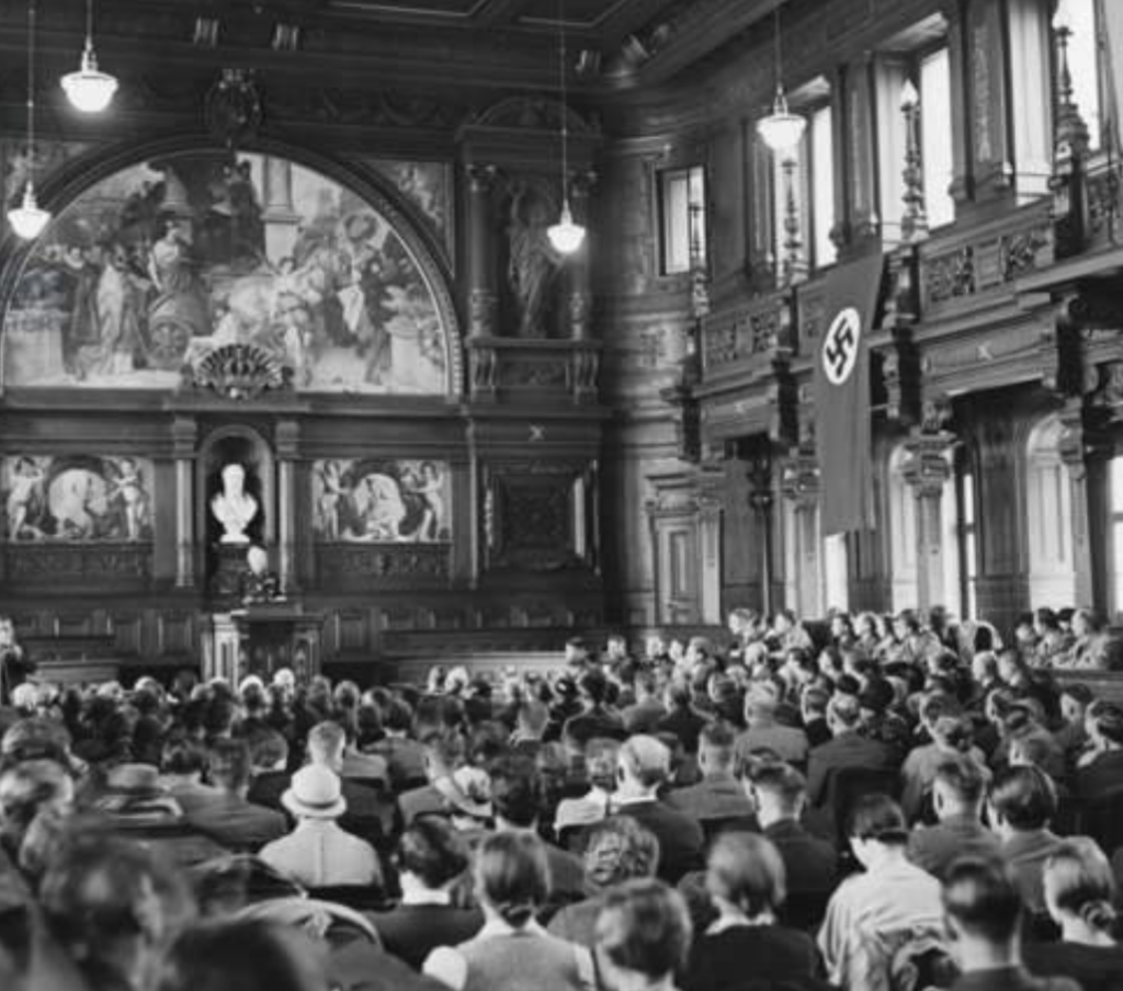 photograph of proceedings at Heidelberg University, led by a Nazi, huge swastika hanging above